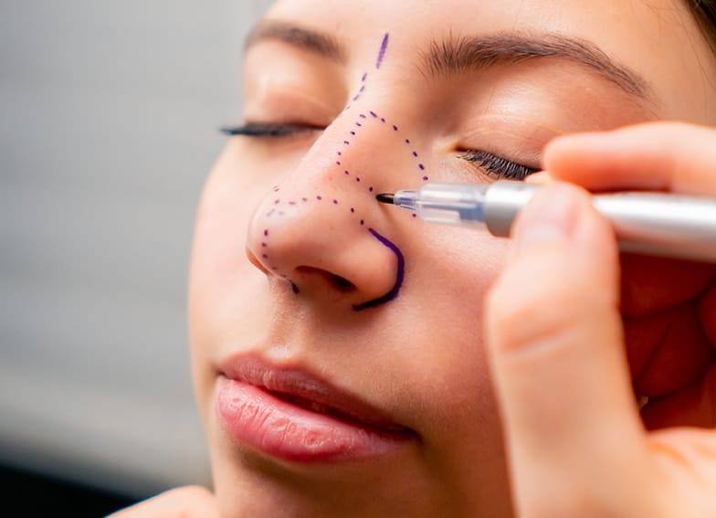 close-up plastic surgeon makes marks on a patient's face during